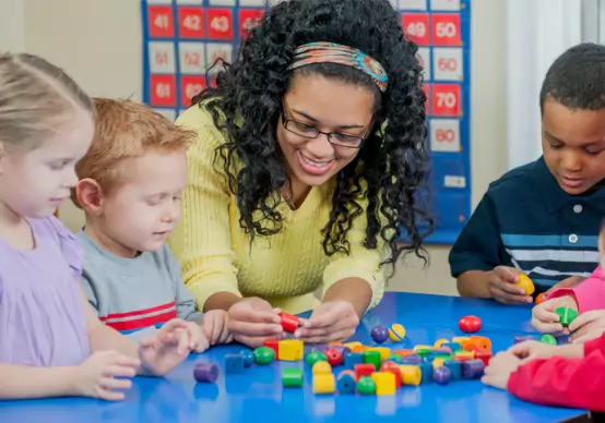 arts-and-crafts-in-preschool A teacher at Embrace Life Child Care, which offers outstanding options for Pre-K by Elmwood IL, helps kids with an arts and crafts project.