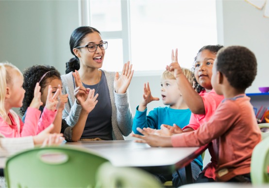 multi-ethnic-preschool-teacher-and-students-in-classroom A teacher at Embrace Life Child Care, a Preschool in Peoria County IL, practices counting with preschoolers.