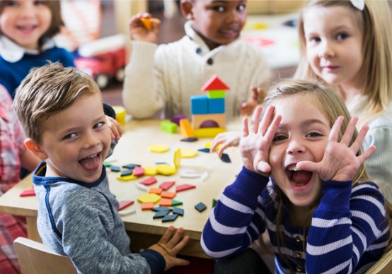 playful-preschoolers Children at Embrace Life Child Care, which provides outstanding Child Care for Princeville IL, smile at the camera while playing with blocks.