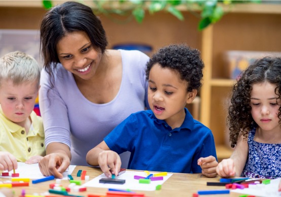 playing-with-blocks A teacher and children at Embrace Life Child Care, a top option for Child Care by Princeville IL, play with blocks.