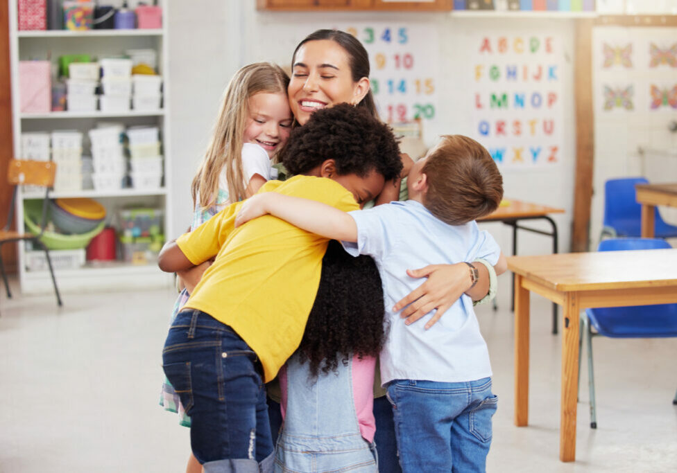 Teacher hugging her toddler students