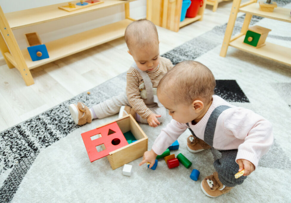 Infants putting blocks in a box matching the shape, developing fine motor skills