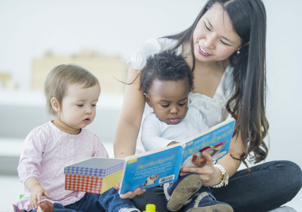 Instructor reading a story to two infants